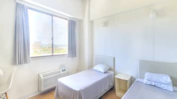 Une chambre d’hôtel avec deux lits, une fenêtre avec des rideaux, un radiateur et une chaise.