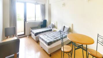 Una habitación con dos camas, una mesita y una silla.