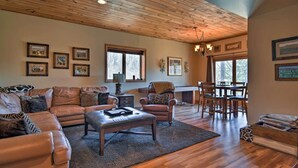 A spacious living room with a wooden ceiling, leather sofas, a dining table with chairs, and framed pictures on the walls. - Beautiful Cabin - Hot Tub & Mtn views - 2 min to Banner Elk & 10 min to ski! (Banner Elk)