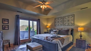 A bedroom with a large bed, a ceiling fan, two bedside lamps, a window with curtains, and a view of the outdoors. - Beautiful Cabin - Hot Tub & Mtn views - 2 min to Banner Elk & 10 min to ski! (Banner Elk)