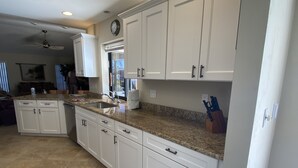 A spacious kitchen with white cabinets, granite countertops, and a large island. - Gorgeous SW Cape Home on canal w/ pool - Southern Exposure  (Cape Coral)