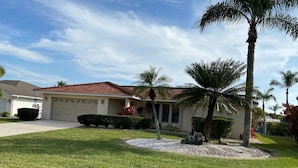 A residential house with a red-tiled roof, a front lawn, and a palm tree. - Gorgeous SW Cape Home on canal w/ pool - Southern Exposure  (Cape Coral)