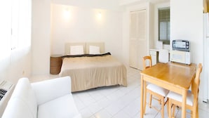 A compact room with a bed, a small dining table with chairs, a kitchenette with a toaster, and a white sofa. - Pia Resort Hotel Corner Studio Room 1 (Tamuning)