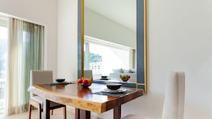 A dining area with a wooden table, two chairs, a bowl of fruit, and a large mirror on the wall. - Zenith 601, 2 Balconies, Spectacular Views, in Zona Romantica, Rooftop Pool/Spa (Puerto Vallarta)
