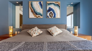 A bedroom with a large bed, two wall-mounted paintings, and bedside lamps. - Zenith 601, 2 Balconies, Spectacular Views, in Zona Romantica, Rooftop Pool/Spa (Puerto Vallarta)