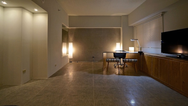 A modern kitchen with a dining area, a flat-screen TV, and a large window with blinds.