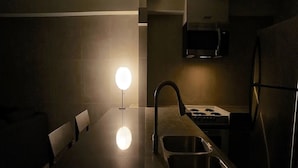 A modern kitchen with a central island, stainless steel sink, and a round light fixture.