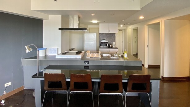 Una cocina moderna con una isla central, electrodomésticos integrados y un comedor con cuatro sillas.