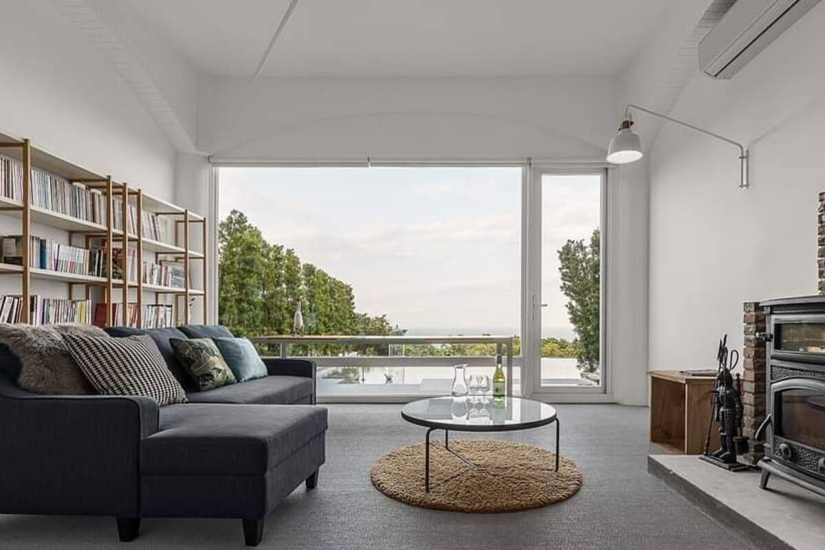 Un salon moderne comprenant un canapé, une table basse, une cheminée et une bibliothèque.