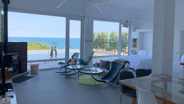 A modern hotel room with a large balcony, a fireplace, and a view of the sea. - Twilight BnB (New Taipei City)