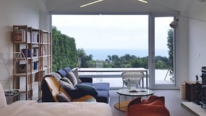 A modern bedroom with a large window, a sofa, a bed, and a bookshelf. - Twilight BnB (New Taipei City)