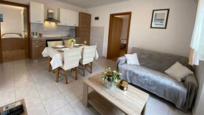 A compact living space with a dining area, kitchenette, and a sofa. - Apartment Maticic dole (Silo - island Krk)