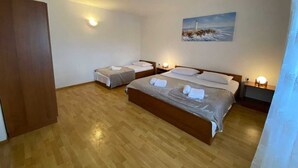 A hotel room with two beds, wooden flooring, a painting on the wall, and bedside lamps. - Apartment Maticic dole (Silo - island Krk)