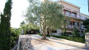 A residential building with a stone pathway, a tree, and a balcony.
