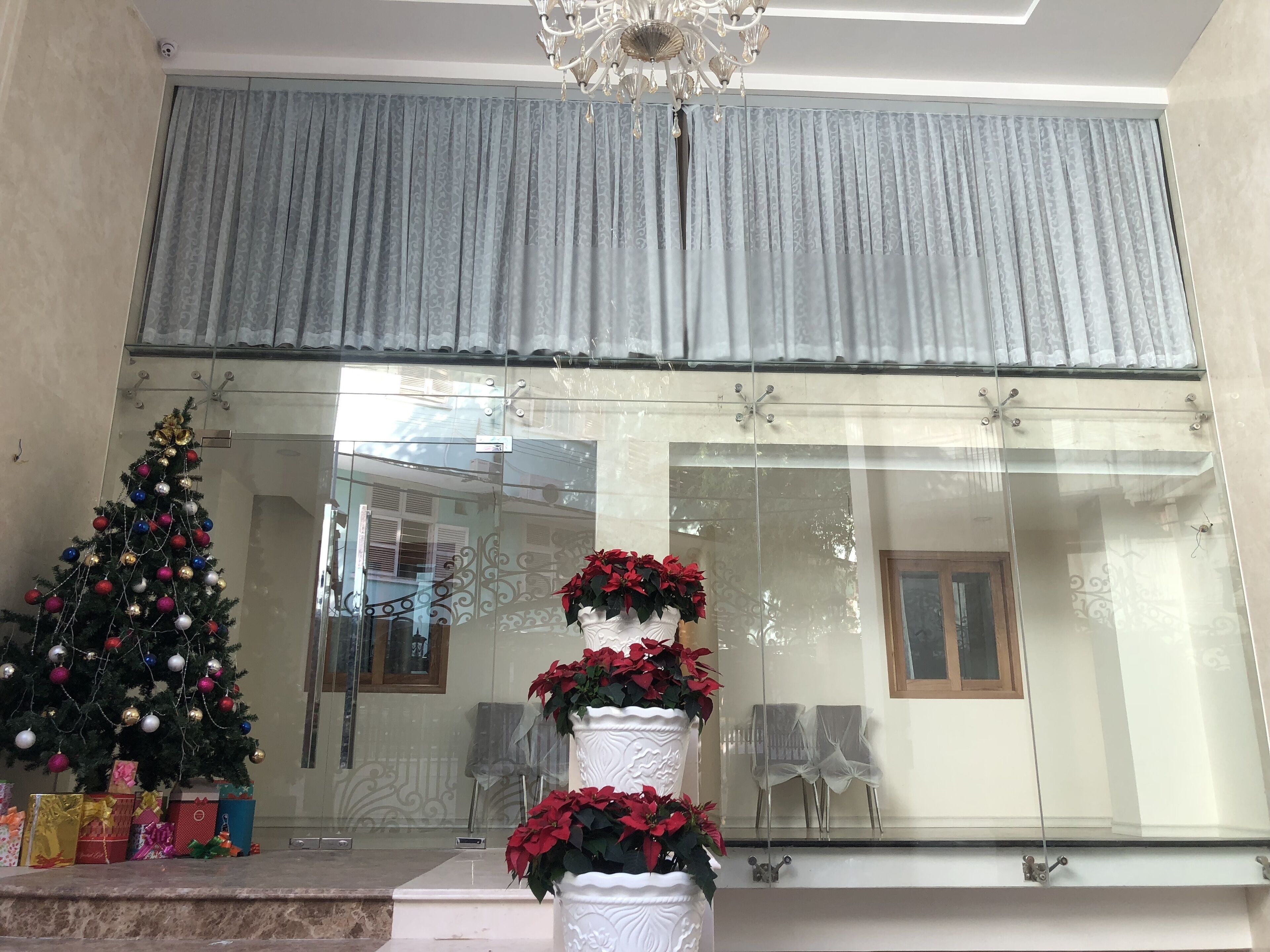 A hotel lobby with a Christmas tree, potted plants, and a large window with curtains.