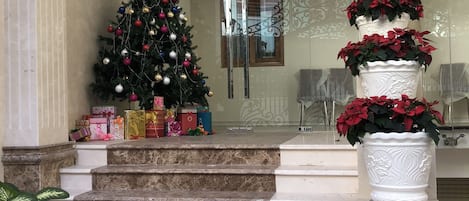 Una escalera que lleva a una puerta decorada con un árbol de Navidad y plantas en macetas.