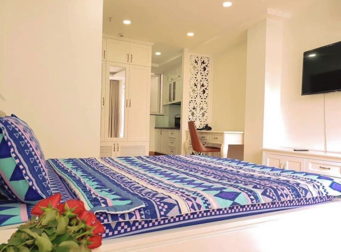 A bedroom with a patterned bedspread, a desk, and a television.