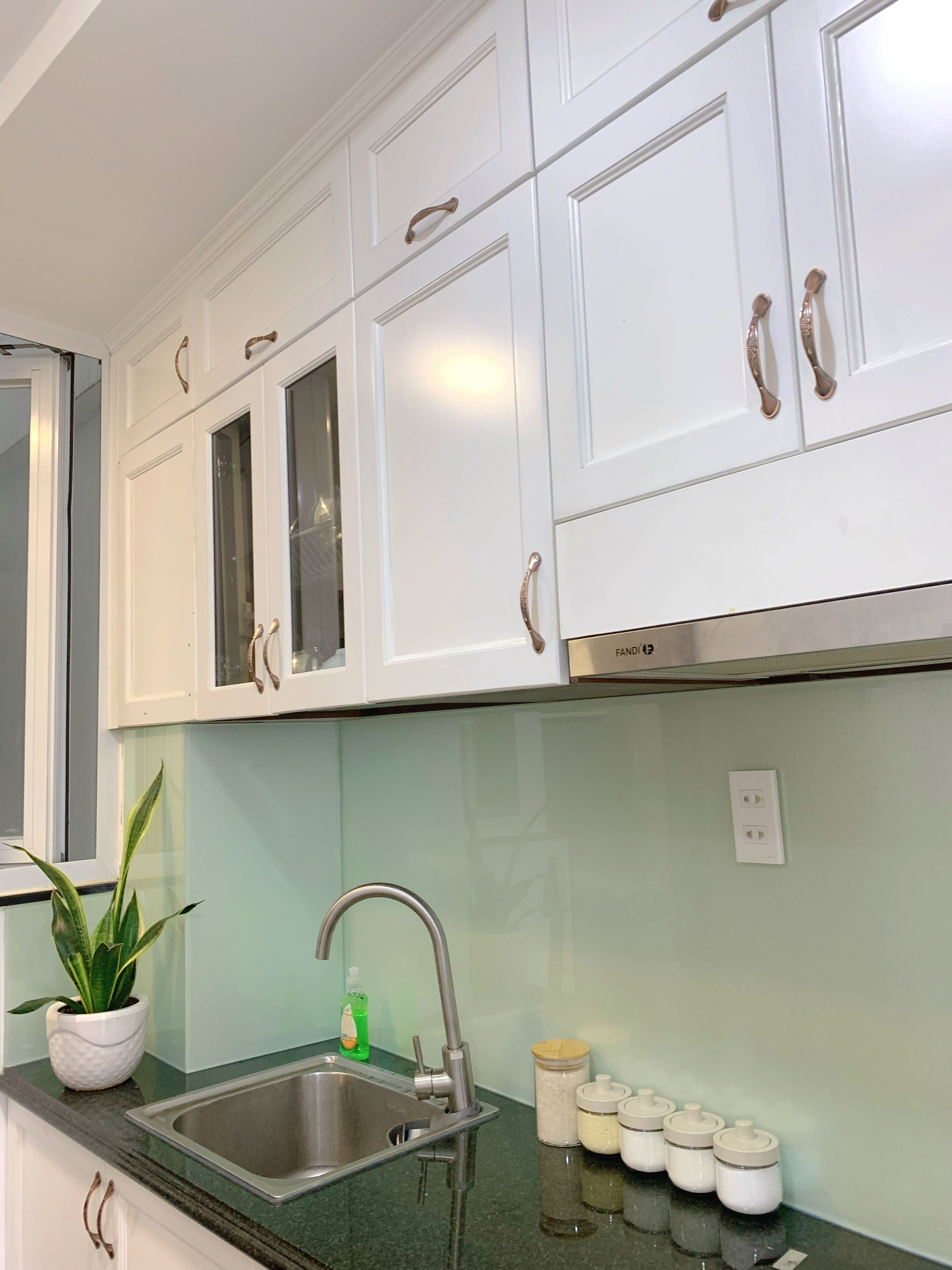 A kitchen with white cabinets, a stainless steel sink, and a green countertop.