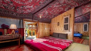 A traditional wooden room with a large bed, a small table with a lamp, and a view of the outdoors. - Hmong Sister House - Hostel (Ta Van)