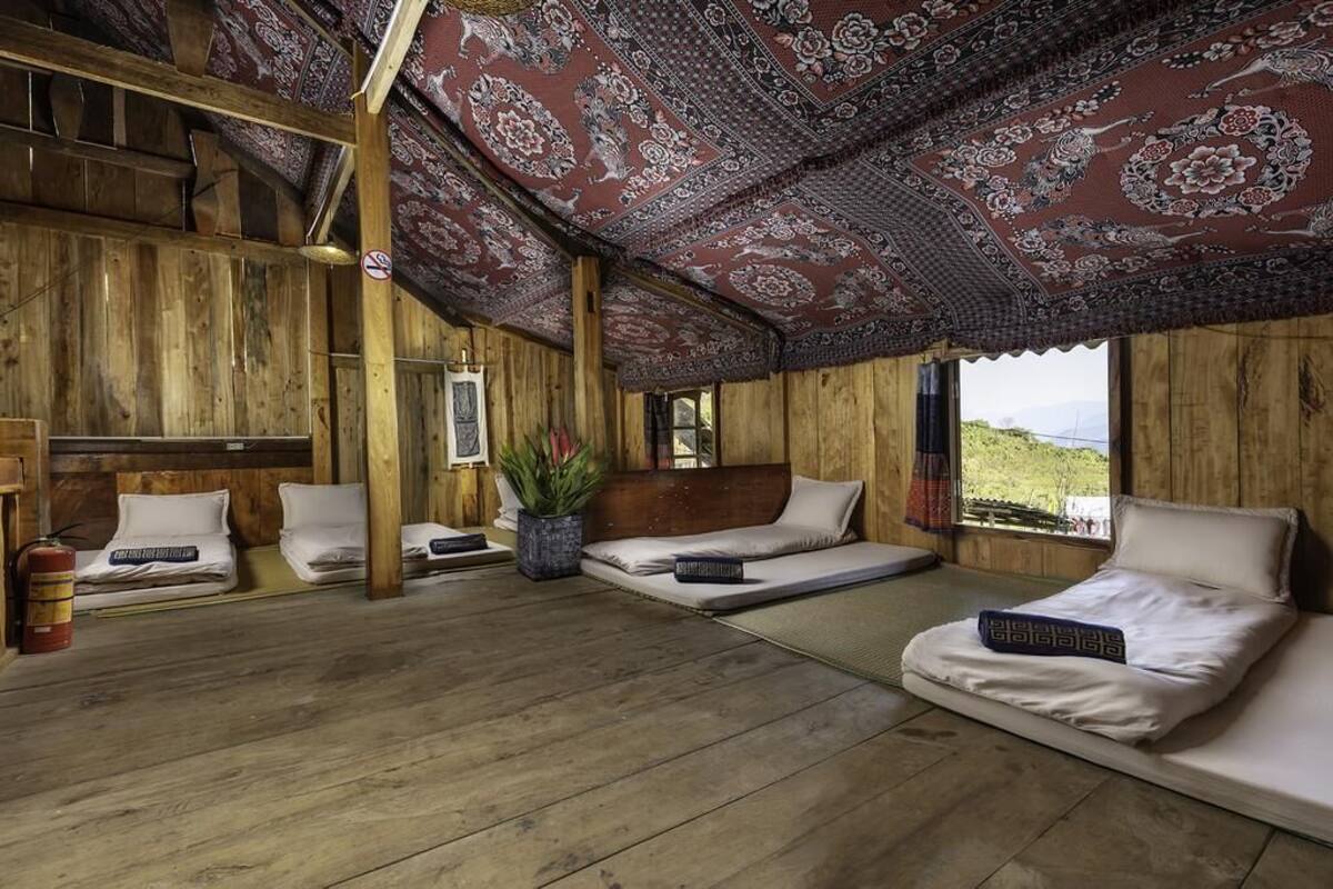 A traditional wooden room with two beds, a fire extinguisher, and a large window.