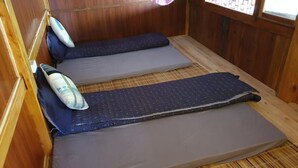 A small, wooden room with two single beds, each with a pillow and a blanket. - Hmong Sister House - Hostel (Ta Van)