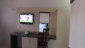 Une chambre d’hôtel comprenant un lit, un bureau avec une chaise, un téléviseur fixé au mur et une armoire.