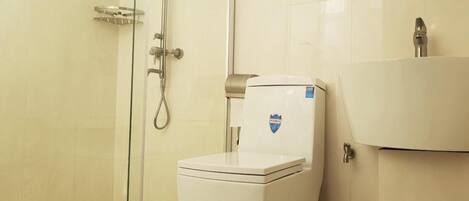 A bathroom with a toilet, a shower, and a sink.