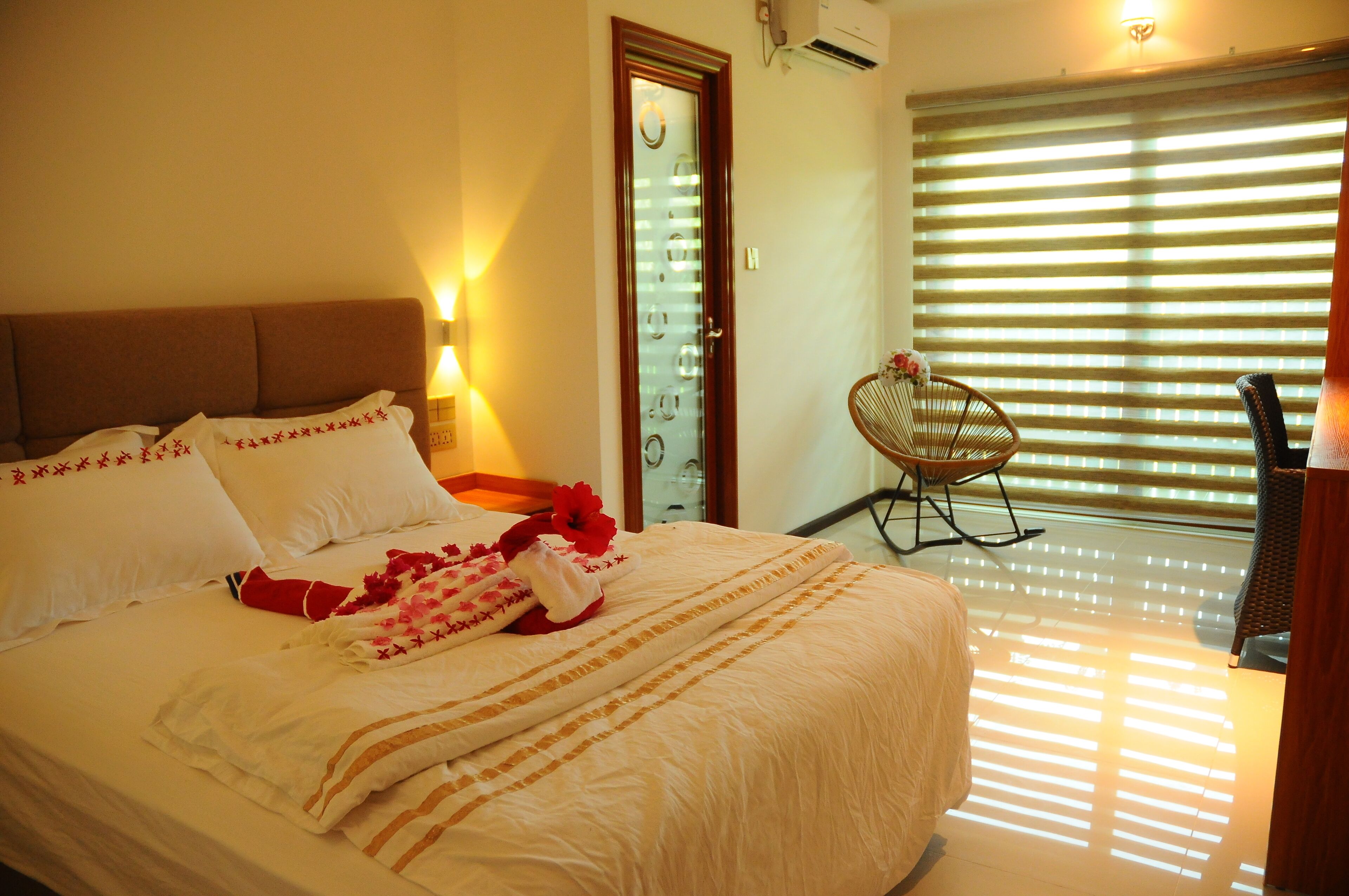 Una habitación de hotel con una cama grande, una silla y un ventanal con persianas.