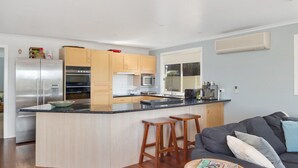 A modern kitchen with a central island, stainless steel appliances, and wooden cabinets. - Surf188 - sleeps up to 16 (SMITHS BEACH)