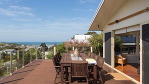 A wooden deck with a table and chairs, overlooking a coastal view. - Surf188 - sleeps up to 16 (SMITHS BEACH)