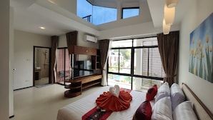 Una habitación de hotel moderna con una cama grande, televisión y balcón con vista a la piscina.