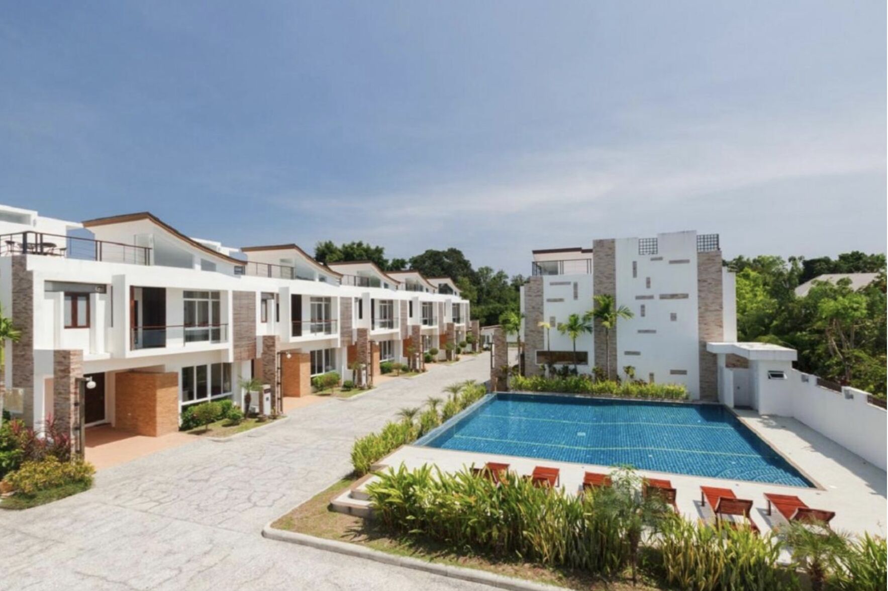 A modern residential complex with a central swimming pool, multiple balconies, and a well-maintained garden area.