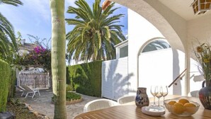 Un patio con una mesa de madera, sillas y un cactus.