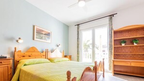 Un dormitorio con cama de madera, mesita de noche, armario y ventana con cortinas.