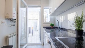 Una cocina moderna con encimera negra, estufa integrada y una planta en maceta.