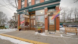 Une devanture de magasin avec une enseigne indiquant une boulangerie et un café, un banc à l’extérieur et un drapeau arc-en-ciel sur le bâtiment.