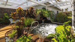 Un espace extérieur abrité, doté d’un jacuzzi, entouré de plantes tropicales et agrémenté d’une cascade.