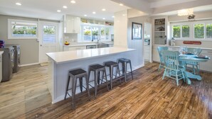 Une cuisine moderne dotée d’un îlot central, de tabourets de bar et d’un coin repas avec une table et des chaises.
