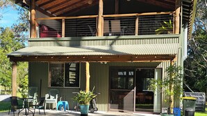 A two-story building with a wooden roof and a covered patio area. - TRANQUIL BUSH RETREAT with
aircon wifi and indoor and outside fires (Brunkerville)