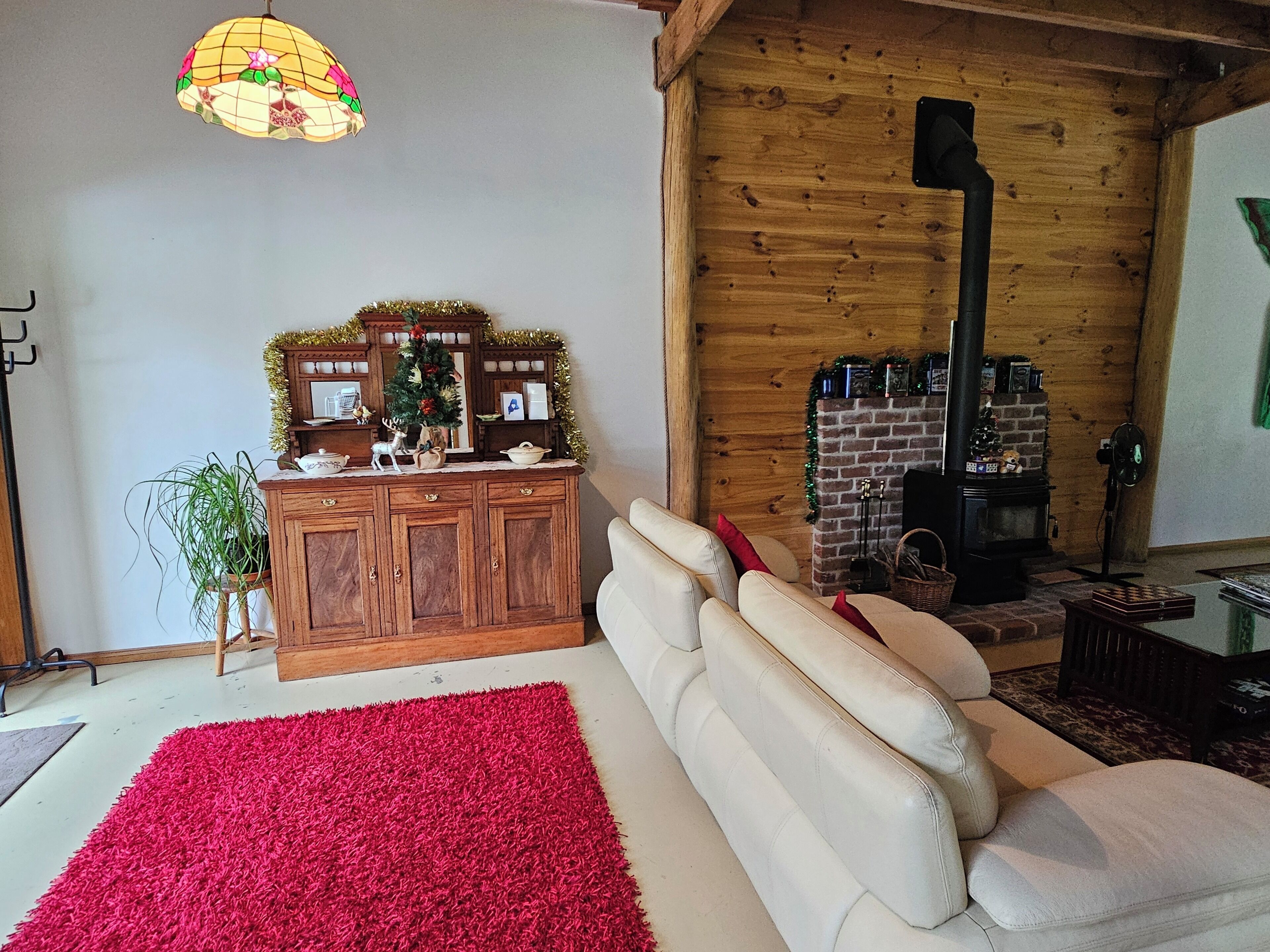 Ein gemütliches Wohnzimmer mit Kamin, Holzwänden und einem roten Teppich.