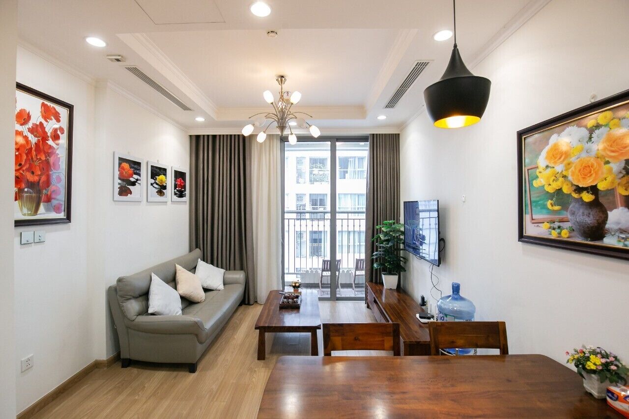 A modern living room with a sofa, coffee table, dining table, and artwork on the walls.