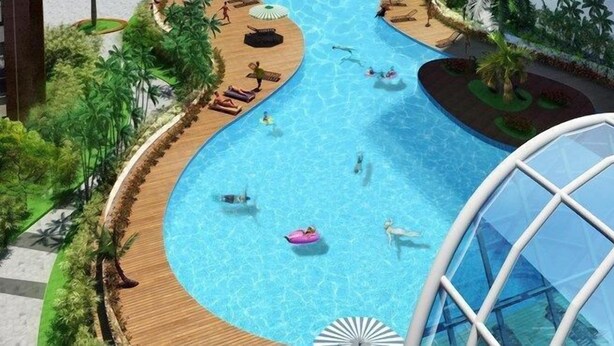 A large indoor swimming pool with multiple lanes, surrounded by wooden deck areas and lush greenery. - Bom Homestay Vinhomes Times City (Hanoi)