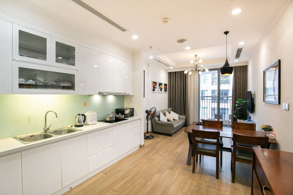 A modern kitchen with white cabinets, a sink, and a dining area with a table and chairs.