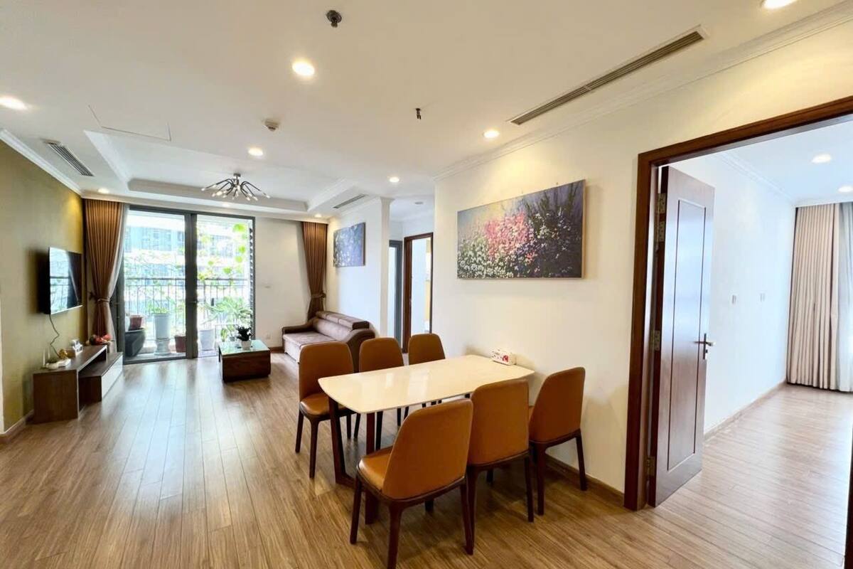 A spacious living area with a dining table, chairs, a sofa, and a TV.
