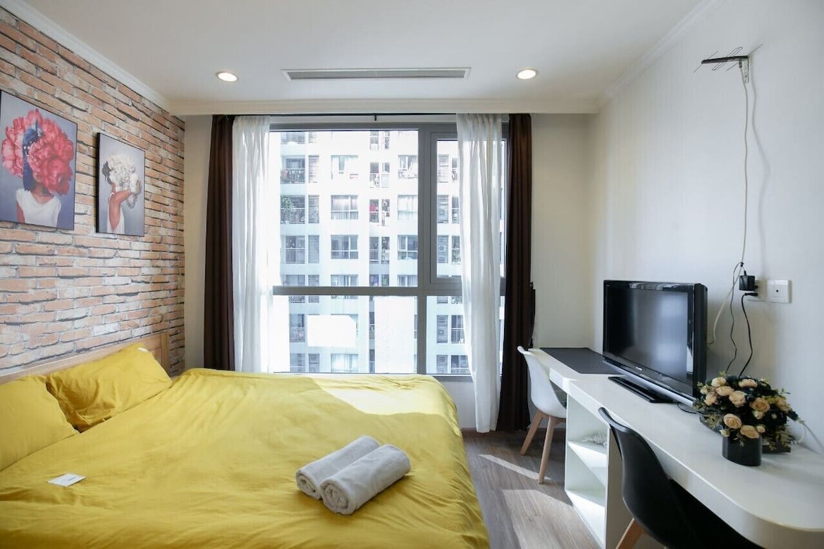 A hotel room with a bed, a desk, a TV, and a window with curtains.