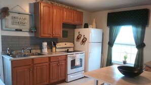 A kitchen with wooden cabinets, a white refrigerator, a stove, and a dining table with a bowl. - Sunset Serenity Relaxation Convenient attached apartment. (Dry Ridge)