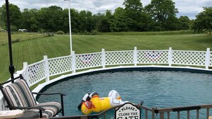 A pool with a 'Please Close the Gate' sign, surrounded by a wooden deck with chairs and an umbrella. - Sunset Serenity Relaxation Convenient attached apartment. (Dry Ridge)