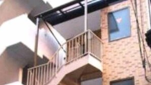 A multi-story building with a spiral staircase leading to an upper balcony. - Hosei Apartment 201 (Kobe)