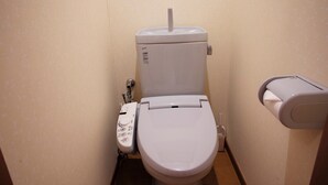 A small, compact bathroom with a toilet, a bidet, and a hand dryer. - Hosei Apartment 201 (Kobe)