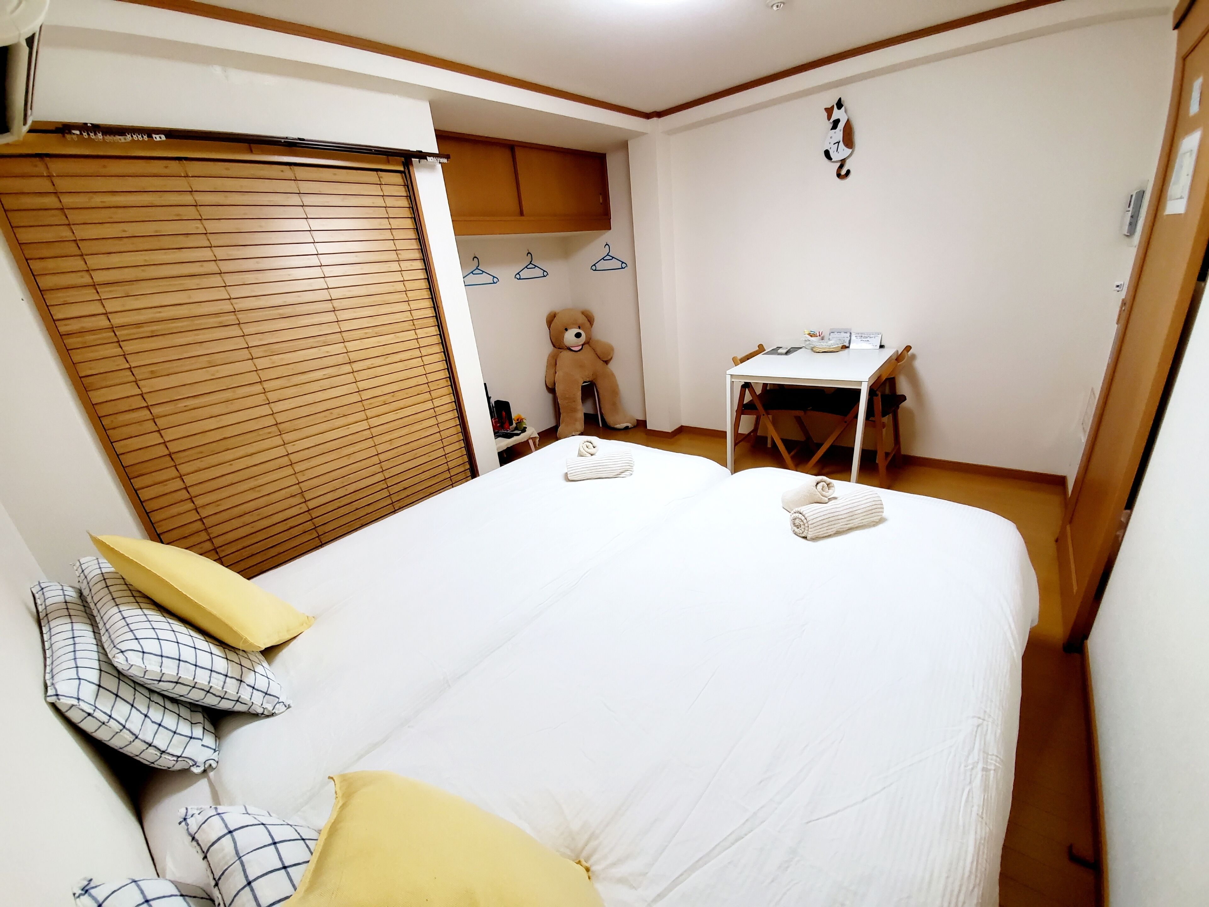 A bedroom with a bed, a desk, a teddy bear, and a wardrobe.